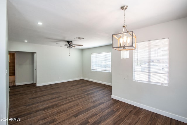 unfurnished room with ceiling fan with notable chandelier and dark hardwood / wood-style flooring