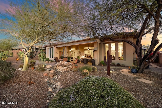 back house at dusk with a patio area and ceiling fan