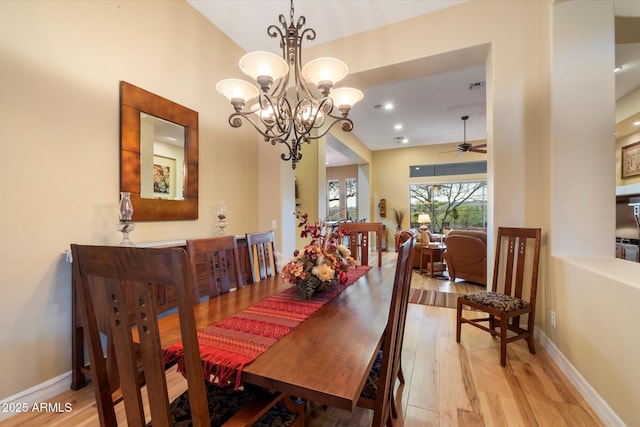 dining space with light hardwood / wood-style flooring and ceiling fan with notable chandelier