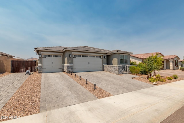 view of front of home featuring decorative driveway, stucco siding, fence, a garage, and stone siding