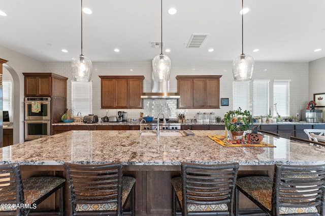 kitchen featuring a large island, double oven, and hanging light fixtures