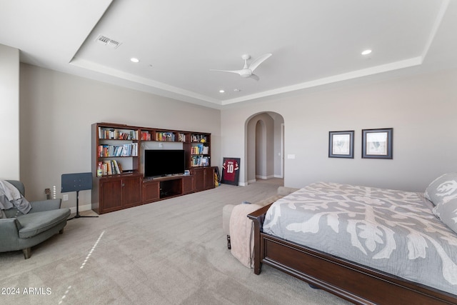 carpeted bedroom with ceiling fan and a tray ceiling