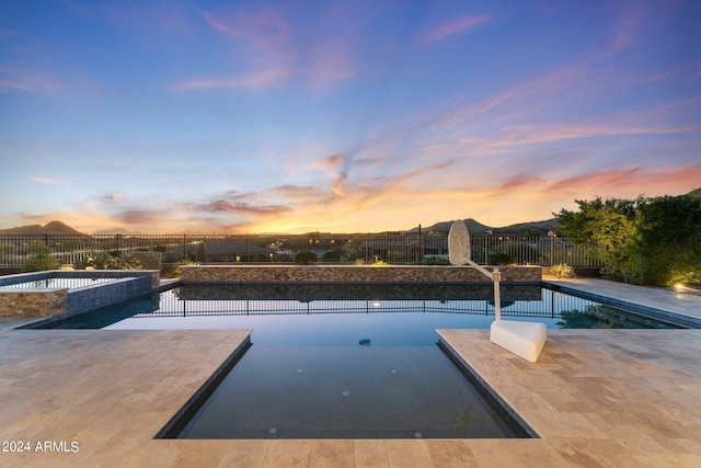 pool at dusk with a patio area