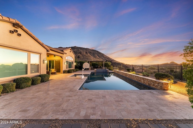 pool at dusk with a mountain view and a patio