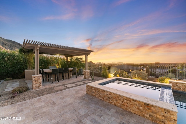 pool at dusk featuring a bar and a patio