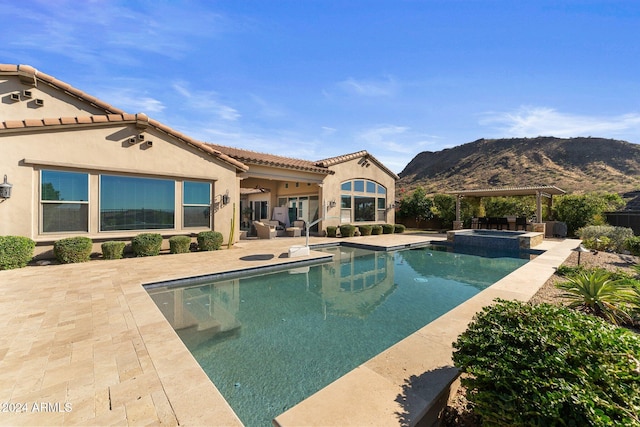 view of pool featuring a patio area, a mountain view, and an in ground hot tub