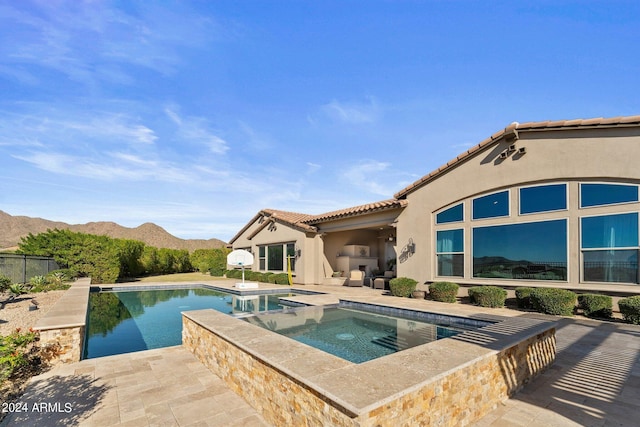 view of pool featuring an in ground hot tub, a mountain view, and a patio area