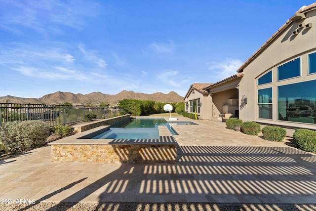 view of swimming pool featuring a patio area, a mountain view, and an in ground hot tub