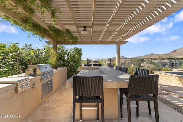 view of patio featuring grilling area, an outdoor kitchen, a mountain view, a pergola, and an outdoor bar