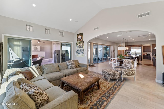 living room featuring light hardwood / wood-style flooring, high vaulted ceiling, and ceiling fan