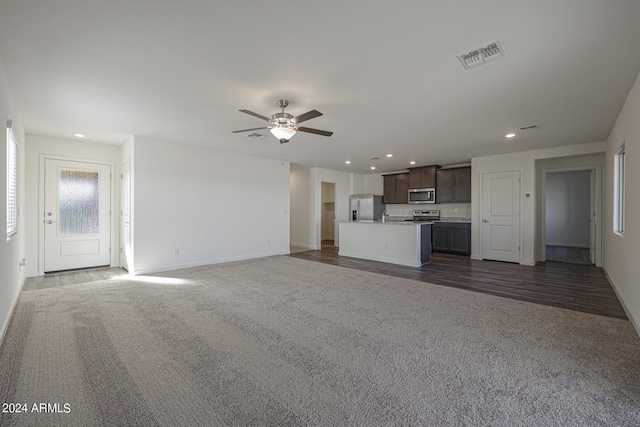 unfurnished living room featuring dark wood-type flooring and ceiling fan