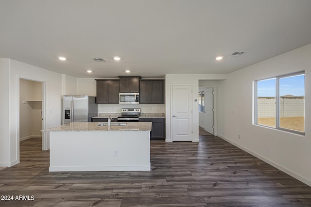 kitchen with dark brown cabinets, a center island with sink, stainless steel appliances, and dark hardwood / wood-style floors