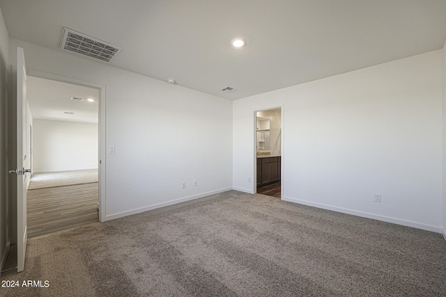 unfurnished bedroom featuring dark colored carpet and ensuite bathroom