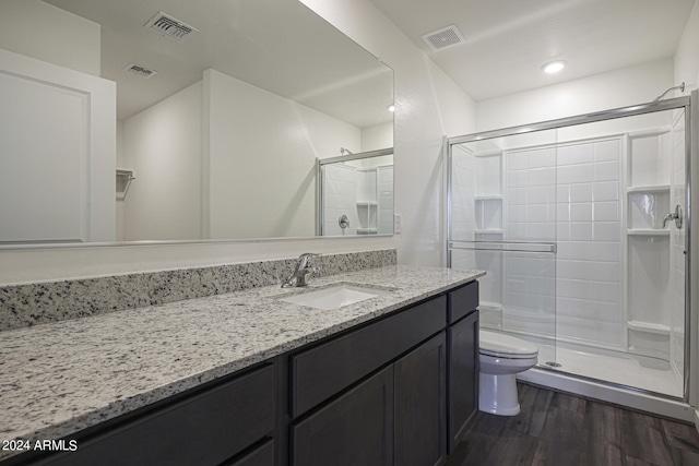 bathroom with an enclosed shower, hardwood / wood-style floors, vanity, and toilet