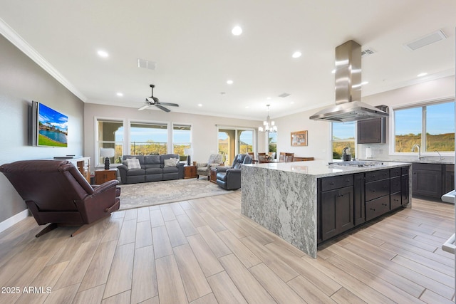 13236 W Montansoro Ln, Peoria, AZ 85383 - kitchen with island exhaust hood, stainless steel gas cooktop, light stone countertops, a ceiling fan, and a chandelier