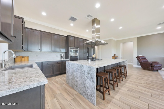 13236 W Montansoro Ln, Peoria, AZ 85383 - kitchen with island exhaust hood, a sink, stainless steel appliances, backsplash, and dark brown cabinets