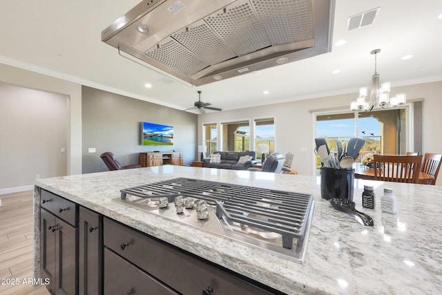 13236 W Montansoro Ln, Peoria, AZ 85383 - kitchen with stainless steel gas stovetop, a chandelier, light stone countertops, light wood-type flooring, and crown molding