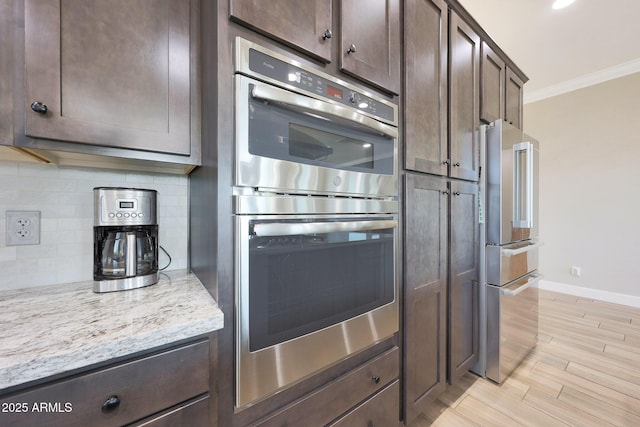 13236 W Montansoro Ln, Peoria, AZ 85383 - kitchen featuring stainless steel appliances, crown molding, dark brown cabinetry, baseboards, and backsplash