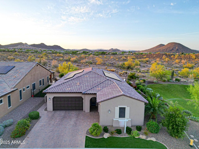 13236 W Montansoro Ln, Peoria, AZ 85383 - view of front facade featuring stucco siding, a mountain view, an attached garage, and roof mounted solar panels