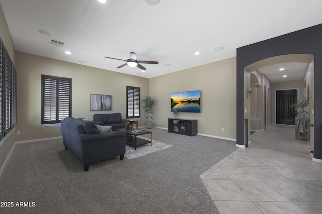 living room with arched walkways, light tile patterned floors, recessed lighting, visible vents, and light carpet