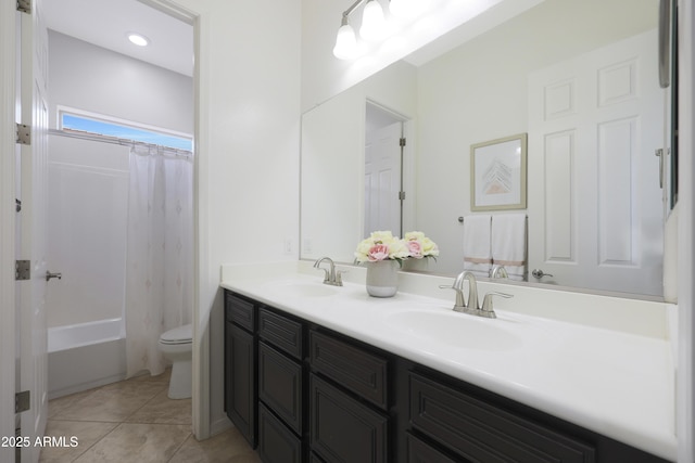 full bathroom featuring toilet, double vanity, a sink, and tile patterned floors