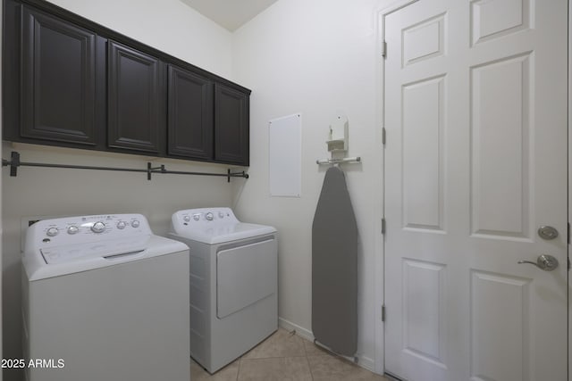 washroom with cabinet space, light tile patterned floors, baseboards, and washing machine and clothes dryer