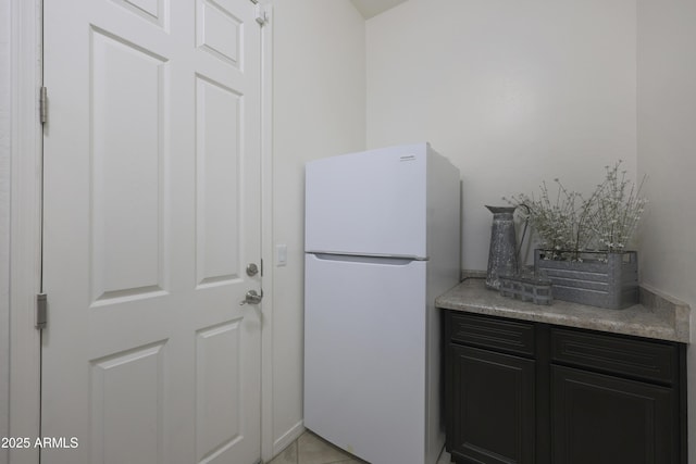 kitchen featuring light countertops, freestanding refrigerator, and dark cabinets