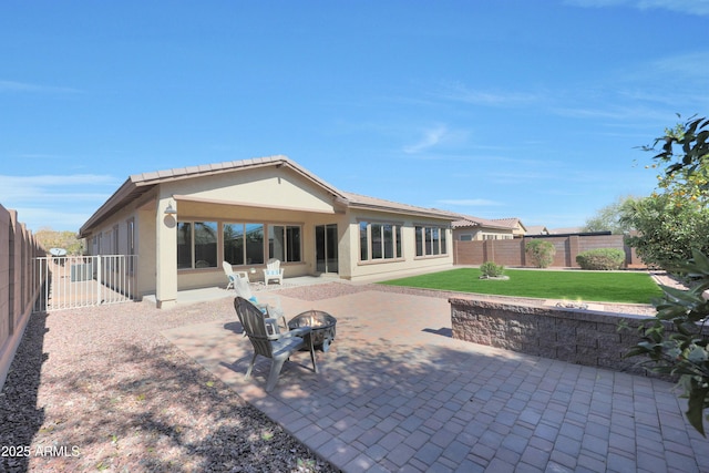 rear view of house featuring a fire pit, a patio, a fenced backyard, a yard, and stucco siding