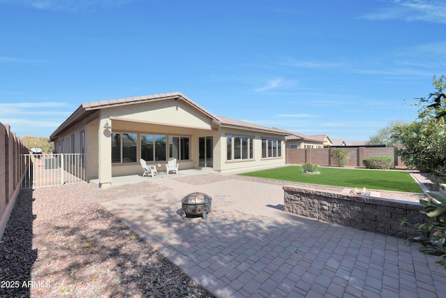 rear view of property with a patio, an outdoor fire pit, a sunroom, a yard, and stucco siding