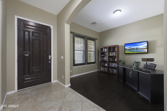 entrance foyer featuring arched walkways, tile patterned flooring, visible vents, and baseboards