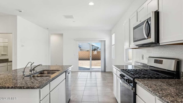 kitchen featuring stainless steel appliances, white cabinets, a center island with sink, and sink