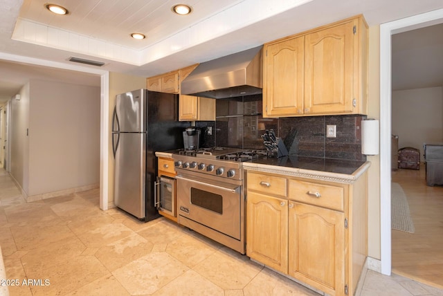 kitchen with backsplash, tile countertops, a raised ceiling, stainless steel appliances, and ventilation hood