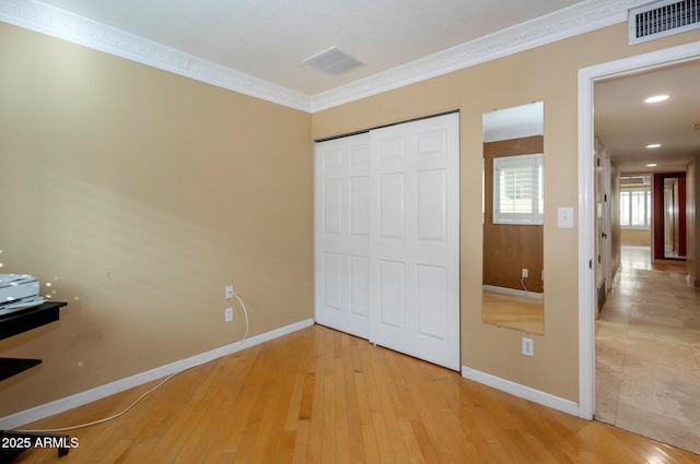 unfurnished bedroom with a closet, ornamental molding, and hardwood / wood-style flooring