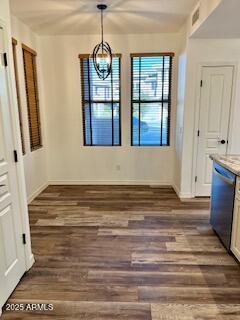 unfurnished dining area with dark wood-style floors, baseboards, visible vents, and a notable chandelier