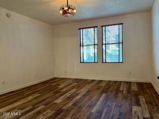 spare room featuring baseboards, a chandelier, and wood finished floors