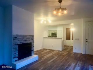 unfurnished living room with a fireplace with raised hearth and wood finished floors