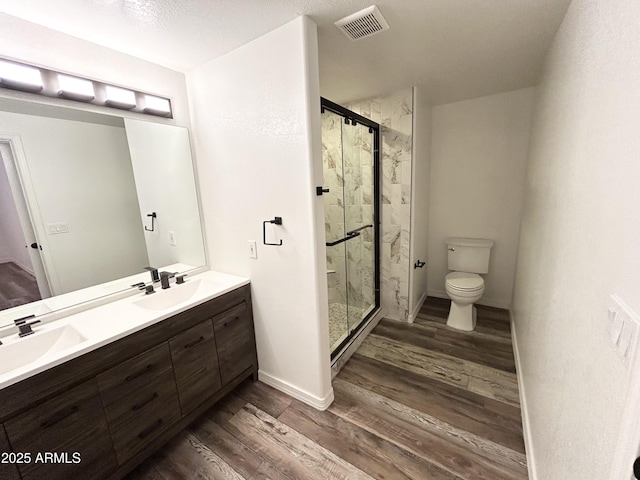 bathroom featuring toilet, visible vents, a sink, and wood finished floors