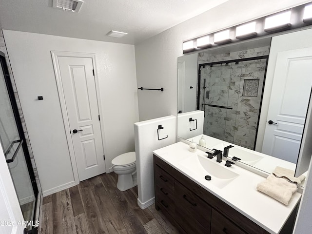 full bath featuring visible vents, toilet, a shower stall, vanity, and wood finished floors