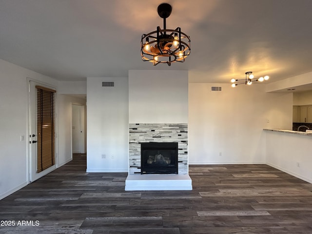 unfurnished living room with wood finished floors, a glass covered fireplace, and visible vents