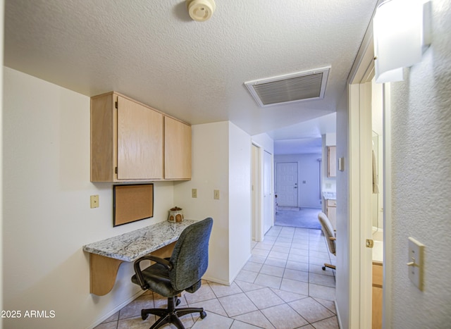 office space with light tile patterned floors, built in study area, a textured ceiling, and baseboards