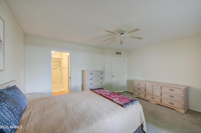 carpeted bedroom with ceiling fan and a textured ceiling