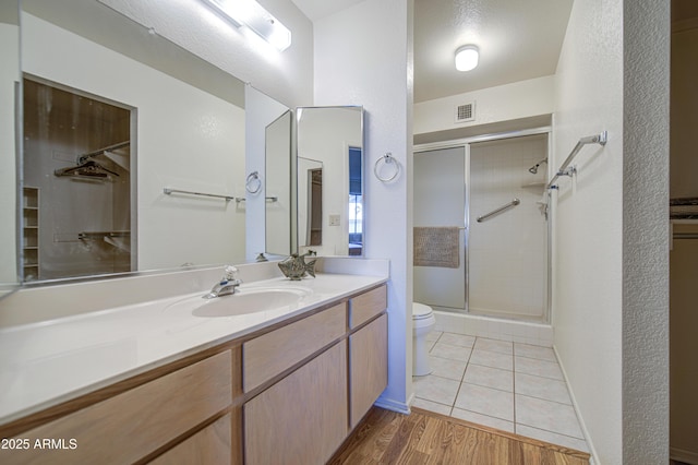 bathroom with toilet, a stall shower, vanity, and wood finished floors