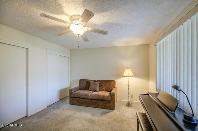 living area with carpet floors, a textured ceiling, and ceiling fan
