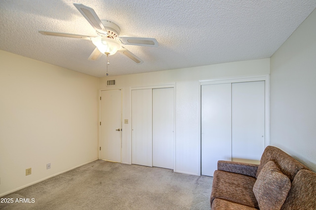 unfurnished room featuring light carpet, ceiling fan, and a textured ceiling