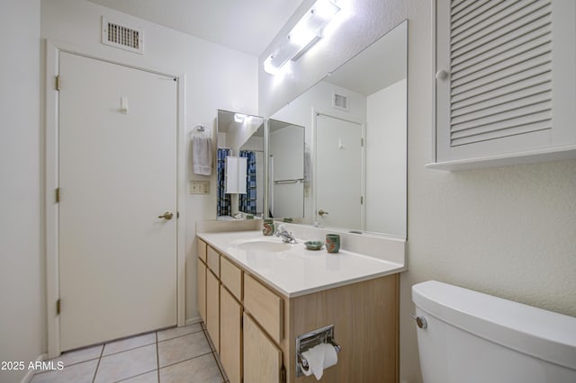 bathroom with toilet, vanity, and tile patterned floors