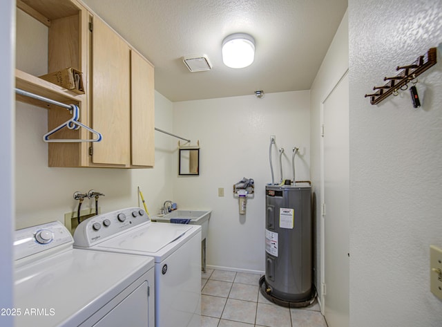 laundry area featuring water heater, independent washer and dryer, cabinet space, light tile patterned flooring, and baseboards
