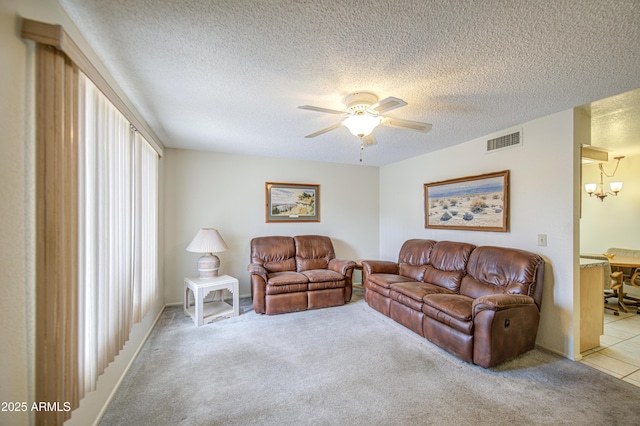 living area featuring ceiling fan, a chandelier, light carpet, and a textured ceiling