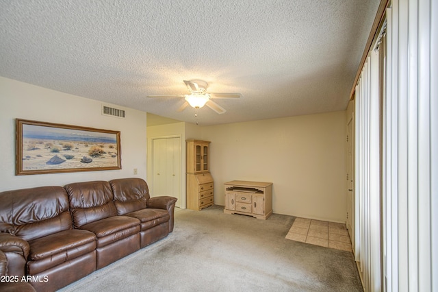 carpeted living room featuring a ceiling fan and a textured ceiling
