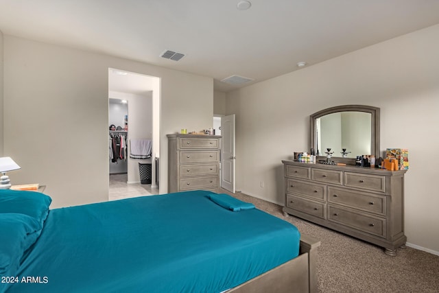 carpeted bedroom with a walk in closet and a closet