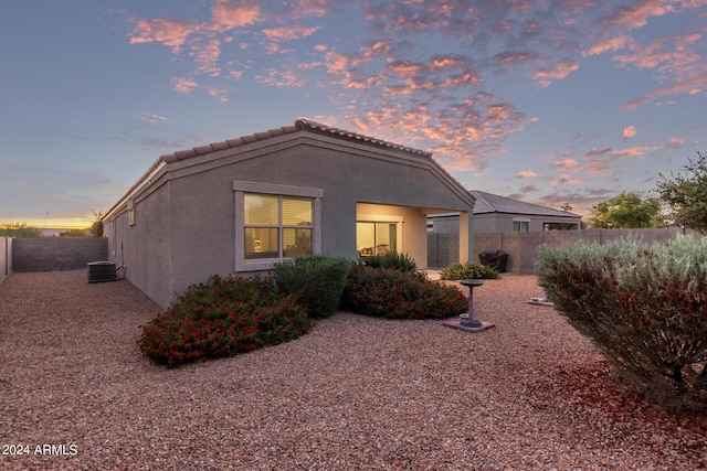 back house at dusk featuring cooling unit